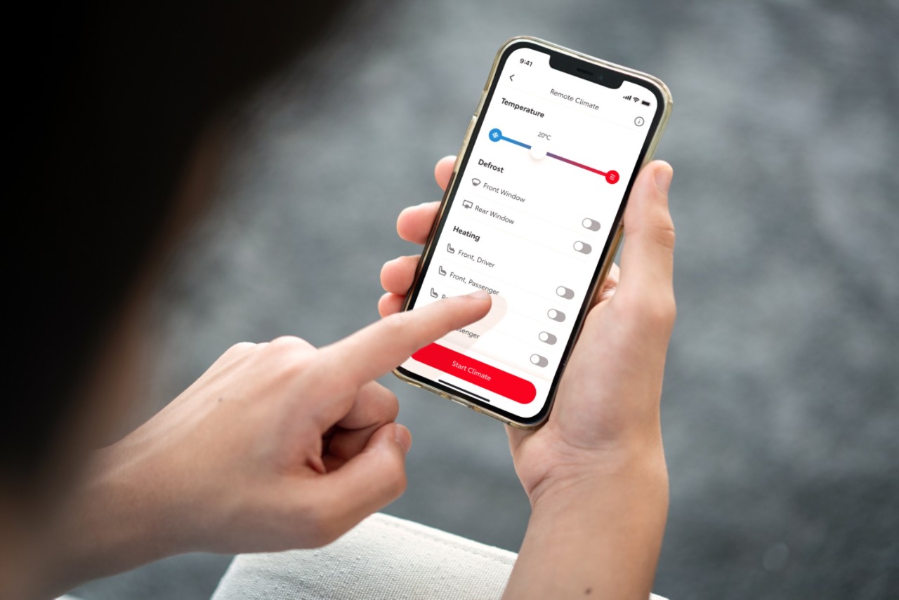 Uma pessoa segura um smartphone enquanto demonstra a app MyToyota. Com a mão esquerda a pessoa altera as definições da Climatização Remota Avançada.